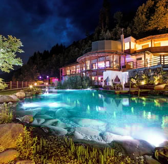 Großer Pool mit Blick auf ein Luxushotel bei Nacht