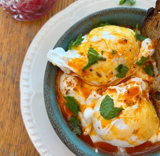 a bowl of eggs on toasted bread with a slice of bread