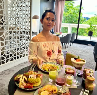 a woman sitting at a table with food and drinks