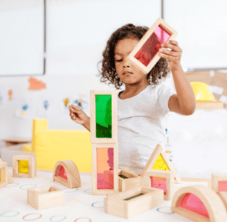 a young girl playing with wooden blocks in a classroom
