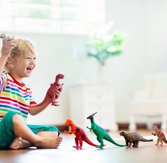 a toddler girl playing with toy dinosaurs