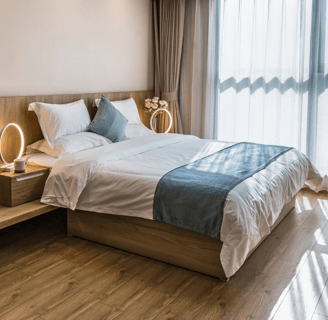 Chambre avec lit double draps bleus et parquet