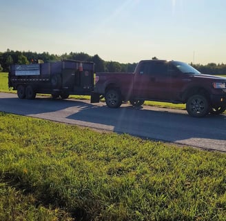 A truck pulling a dump trailer in nature.