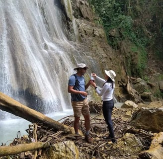 a man and woman standing in front of a waterfall