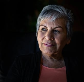 a woman with grey hair and a pink top