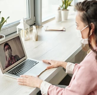 a woman in a pink shirt is sitting at a desk with a laptop