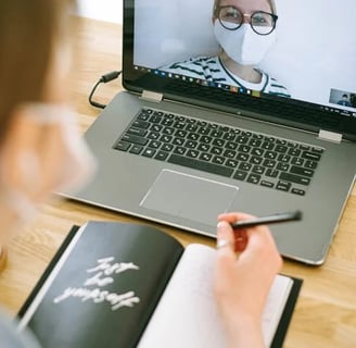 a woman in a mask mask and glasses is looking at a laptop computer screen