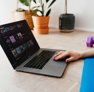 a woman sitting on a yoga mat with a laptop