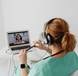 a woman in a green shirt is sitting at a desk with a laptop and head