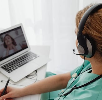 a woman in a green scrub suit is sitting at a desk with a laptop and