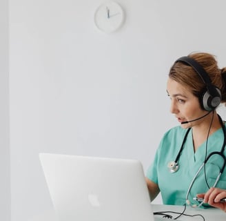 a nurse in a green scrub suit and a stethoscope on a laptop