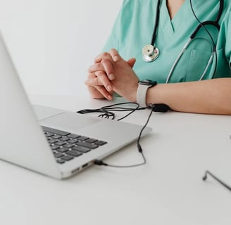 a nurse in scrubs and a stethoscope on a laptop