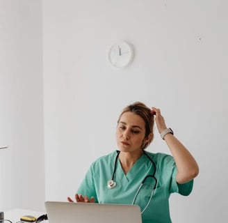 a woman in a green scrub suit sitting at a desk