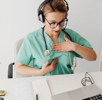 a nurse in a green scrubsuit is holding her hands on her chest