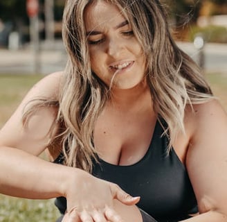 a woman in a black swimsuit sitting on a bench in the grass