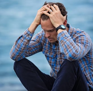 a man sitting on a bench with his hands on his head