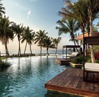 Image of a poolside cabana with palm trees and an ocean view.