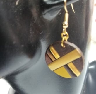 a pair of earrings with leather and gold accents