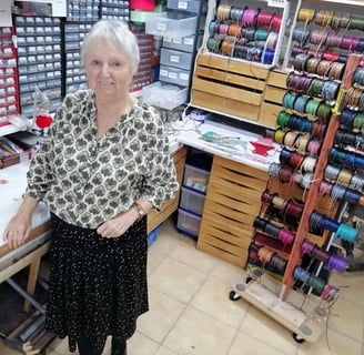 a woman standing in a sewing room with a lot of thread thread spools