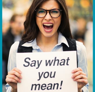 a woman holding a sign saying say what you mean