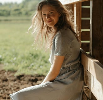 Young lady at a farm, wearing an eco-friendly dress, probably made of linen or hemp.