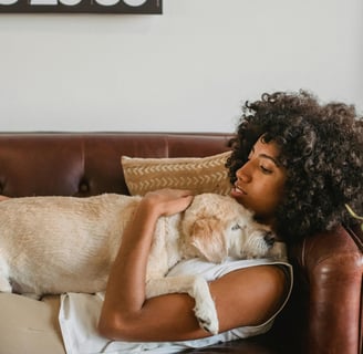 woman laying on couch hugging a dog on her chest