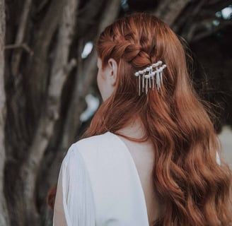 Bride in white wedding dress and loose curls, wearing pearl hair pins and a braid