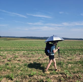 Woman hiking with an umbrella through field