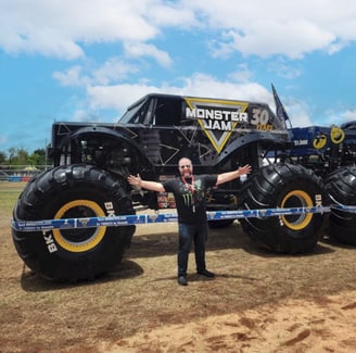 a man standing in front of a custom wrapped monster truck