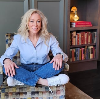 a blonde woman sitting in a chair in a home library