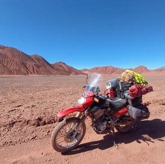 a motorcycle parked in the desert with a backpack on it cono de arita puna atacama salar