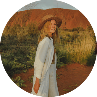 portrait of young woman in a hat standing in front of Uluru, Australia