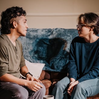 two actors sitting on a couch portraying best friends in anew original play by Trent Clifford.