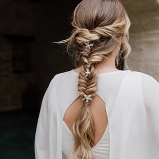 Blonde bride wearing her hair in a fishtail braid and pearl hair accessories
