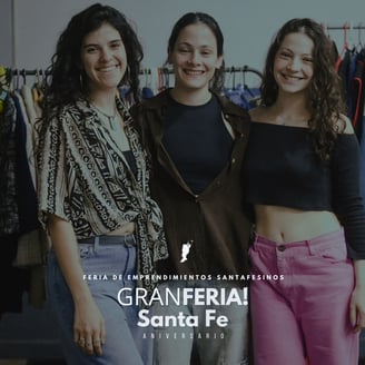 three women standing in front of a clothing rack