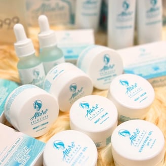 Various Allors Skin Care products, including night creams, serums, and soaps, displayed on a soft surface with a blue