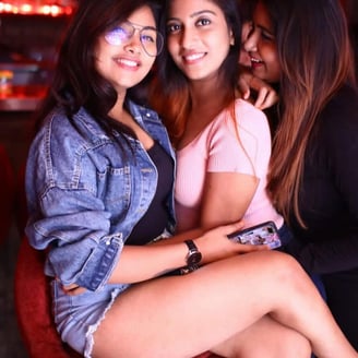 two women sitting on a red chair in a bar
