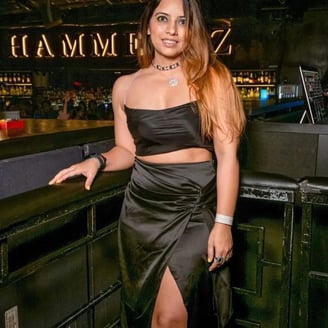 a woman in a black dress standing in front of a bar