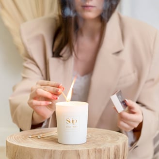 a woman is holding a match and burning a candle