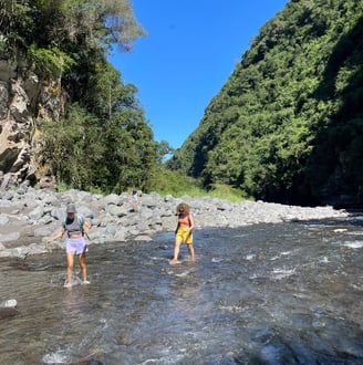 two people standing in a river with a mountain in the background
