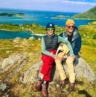 a man and woman sitting on a rock in the mountains of the Lofoten islands | Island hopping