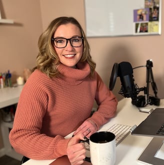 Jennifer in a pink sweater and glasses sitting at a desk