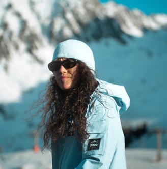 Une femme à la montagne habillé d'une veste bleue de la marque DOPE.