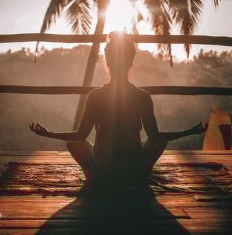 Frau meditiert im Schneidersitz im Sonnenaufgang