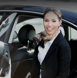 a woman in a suit and tie is standing in front of a chauffeur car