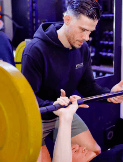 A personal trainer assisting his client perform a bench press exercise