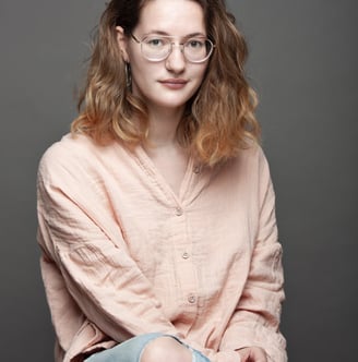 Une femme avec une chemise rose et un jean sur un fond gris
