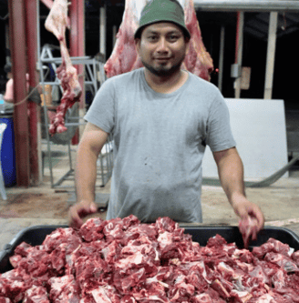 a man standing in front of a large pile of meat