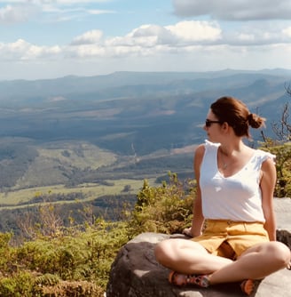 a woman sitting on a rock with a view of the mountains