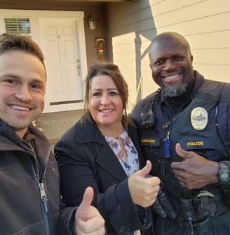 Alex standing with home owners next to their home. A happy husband and wife.